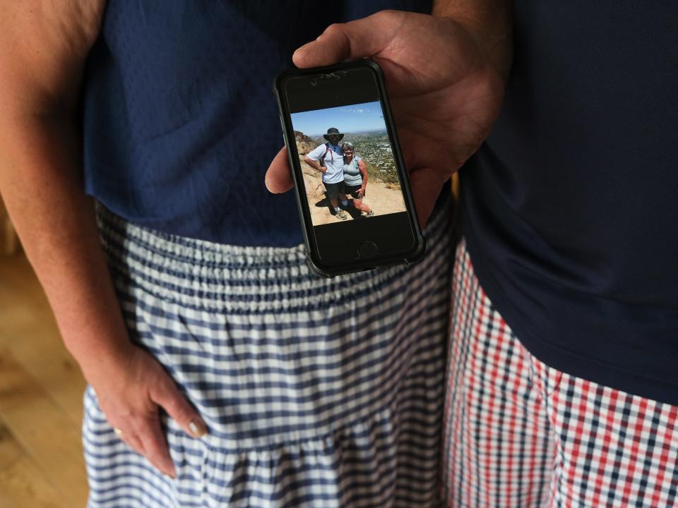 A hand holding a phone, with a photo of Lois and her husband on their hike on the day of the incident.