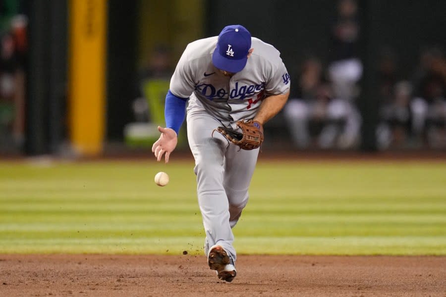 Los Angeles Dodgers third baseman Max Muncy bobbles the ball before throwing to first for the out on Arizona Diamondbacks’ Gabriel Moreno during the second inning in Game 3 of a baseball NL Division Series, Wednesday, Oct. 11, 2023, in Phoenix. (AP Photo/Ross D. Franklin)