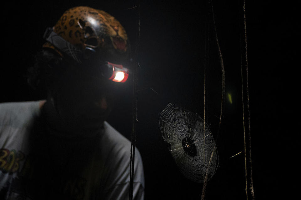 Raul Padilla, member of the Jaguar Wildlife Center which works to protect jaguars, shines his headlamp on a spiderweb inside the miles-long cave system "Garra de Jaguar," or the Paw of the Jaguar, underneath the planned route of the Maya Train in Playa del Carmen, Quintana Roo state, Mexico, Thursday, Aug. 4, 2022. Mexican President Andres Manuel Lopez Obrador wants to finish the entire train in 16 months by filling the caves with cement or sinking concrete columns through the caverns – the only places that allowed humans to survive in this area. (AP Photo/Eduardo Verdugo)