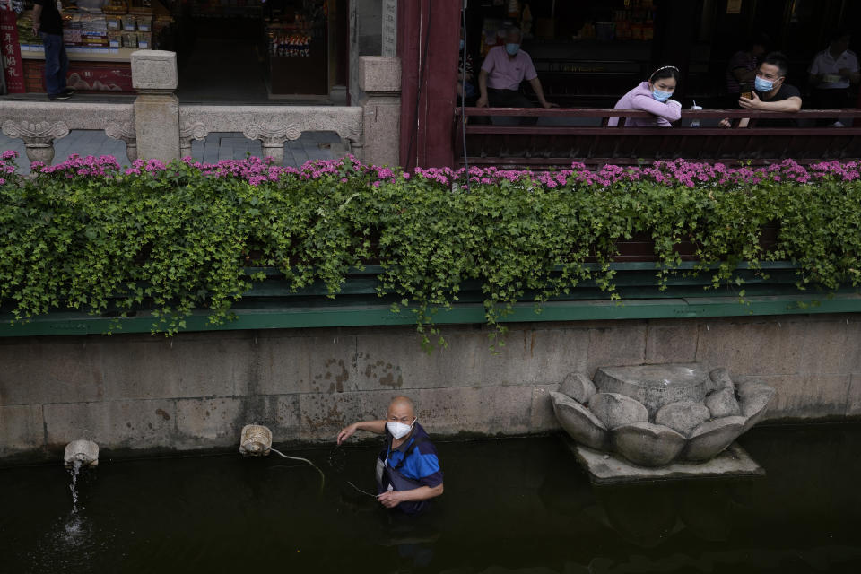 A worker repairs a fountain as visitors rest near in the Yu Garden Mall, Thursday, June 2, 2022, in Shanghai. Traffic, pedestrians and joggers reappeared on the streets of Shanghai on Wednesday as China's largest city began returning to normalcy amid the easing of a strict two-month COVID-19 lockdown that has drawn unusual protests over its heavy-handed implementation. (AP Photo/Ng Han Guan)