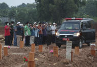 Residents pray outside an ambulance carrying coffins of two COVID-19 victims before their burial at the special section of the Pedurenan cemetery in Bekasi, West Java, Indonesia, Friday, July 30, 2021. Indonesia surpassed the grim milestone of 100,000 official COVID-19 deaths on Wednesday, Aug. 4, 2021, as the country struggles with its worst pandemic year fueled by the delta variant, with growing concerns that the actual figure could be much higher with people also dying at home. (AP Photo/Achmad Ibrahim)