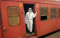 A Sri Lankan railway worker in hazmat suit travels in a train coach in Colombo, Sri Lanka, Monday, May 11, 2020. Sri Lanka's government asked state and private sector workers to resume work Monday after a nearly two-month coronavirus lockdown. (AP Photo/Eranga Jayawardena)