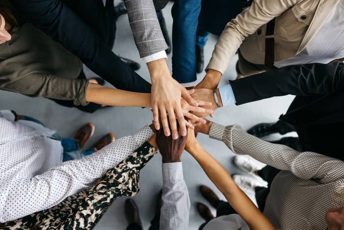 people putting their hands together in an office