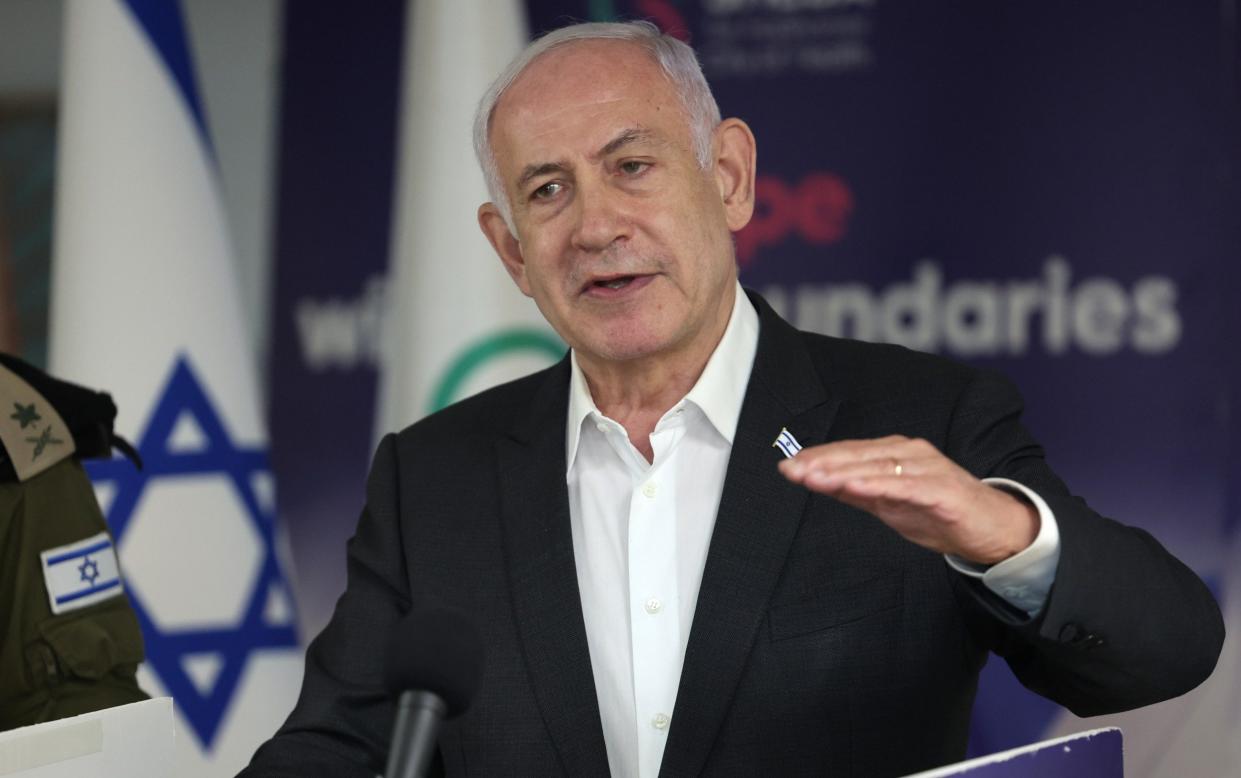 Benjamin Netanyahu speaks at a press conference, with an Israeli flag behind him