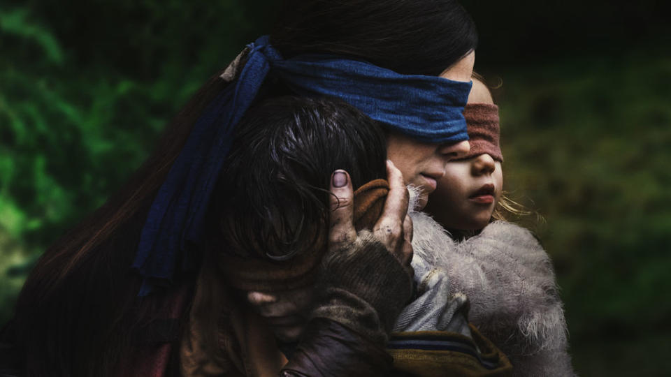 Sandra Bullock blindfolded and holding two kids in "Bird Box."