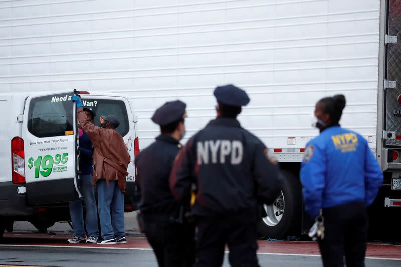 NYPD officers stand by as workers secure a van full of bodies, during the outbreak of coronavirus disease (COVID-19) at the Andrew Cleckley Funeral Home in Brooklyn, New York