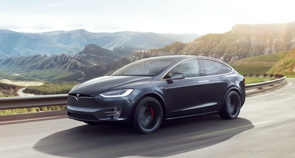A black Tesla Model X SUV on a mountain road.
