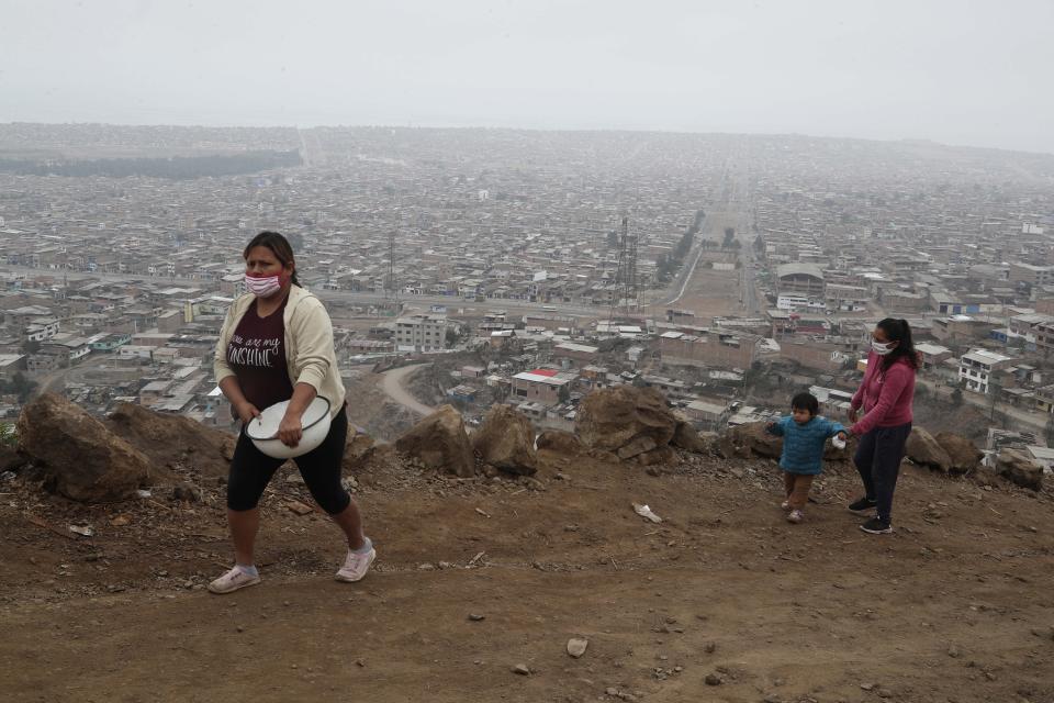 Mujeres que enfrentan dificultades por la pandemia del nuevo coronavirus se dirigen a recibir comida en Villa María del Triunfo en Lima, Perú. (AP Foto/Martin Mejia)