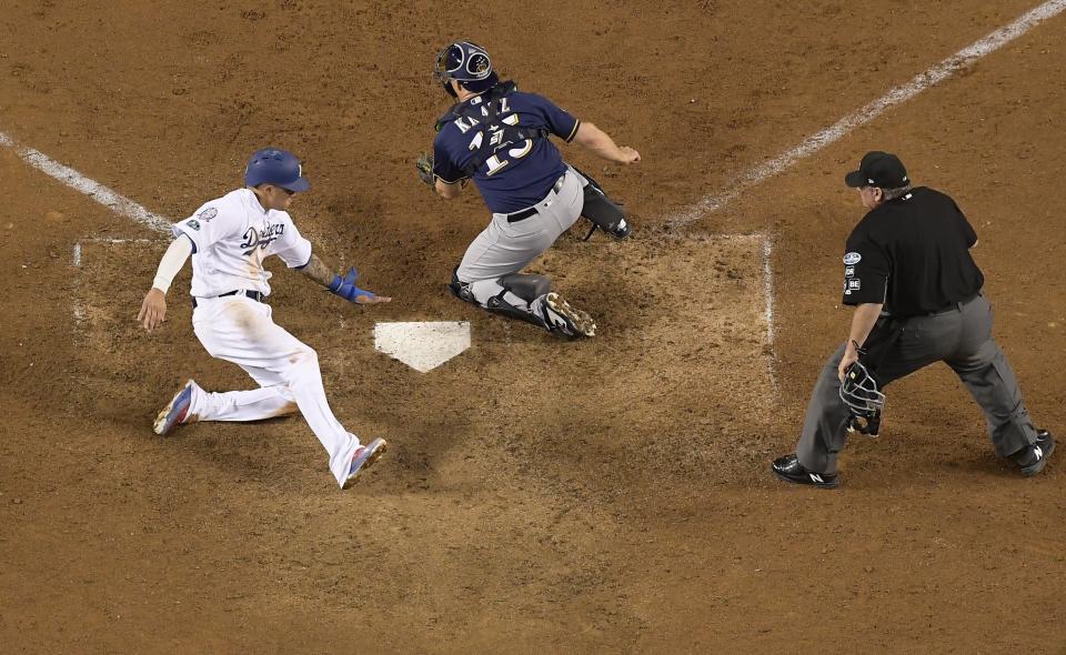 Manny Machado de los Dodgers de Los Ángeles anota la carrera de la victoria frente al receptor Erik Kratz de los Cerveceros de Milwaukee en el cuarto juego de la Serie de Campeonato de la Liga Nacional. Los Dodgers ganaron 2-1 tras 13 innings. (AP Foto/Mark J. Terrill)