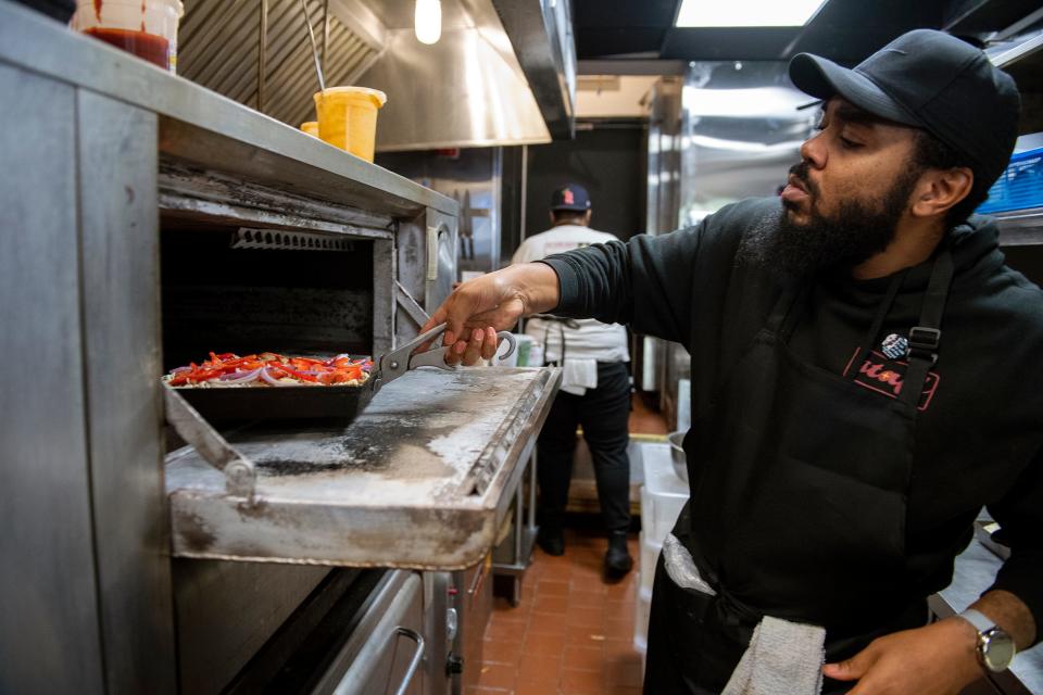 Executive chef Michael Carter loads a pizza into the oven at Down North in Philadelphia.