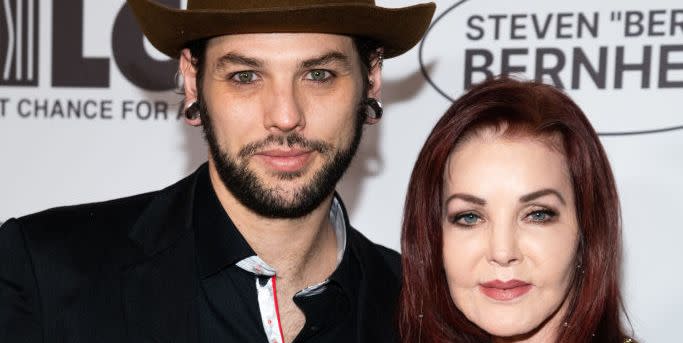 navarone garibaldi and priscilla presley smiling for a photo in front of an event backdrop