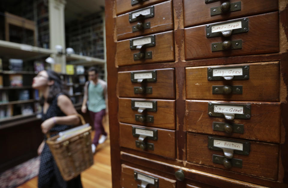 Brown University students Nicha Ratana-Apiromyakij, left, and Nick Melachrinos, walk past a card catalog, right, at the Providence Athenaeum, in Providence, R.I., Monday, July 15, 2013. With roots dating back to 1753, the private library is one of the oldest in the country. It is housed in a Greek Revival-style granite building that neighbors Brown University and the Rhode Island School of Design. (AP Photo/Steven Senne)