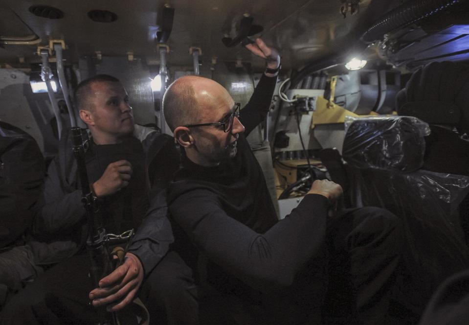 FILE - In this May 7, 2014 file photo, Ukrainian Prime Minister Arseniy Yatsenyuk, right, inspects a Ukrainian army APC on the road at Slovyansk, Ukraine. Yatsenyuk’s interim government is seeking to carry out sweeping reforms to break from a culture of self-interest, cynicism and corruption that left the country on the verge of bankruptcy. (AP Photo/Andrew Kravchenko, Pool, File)