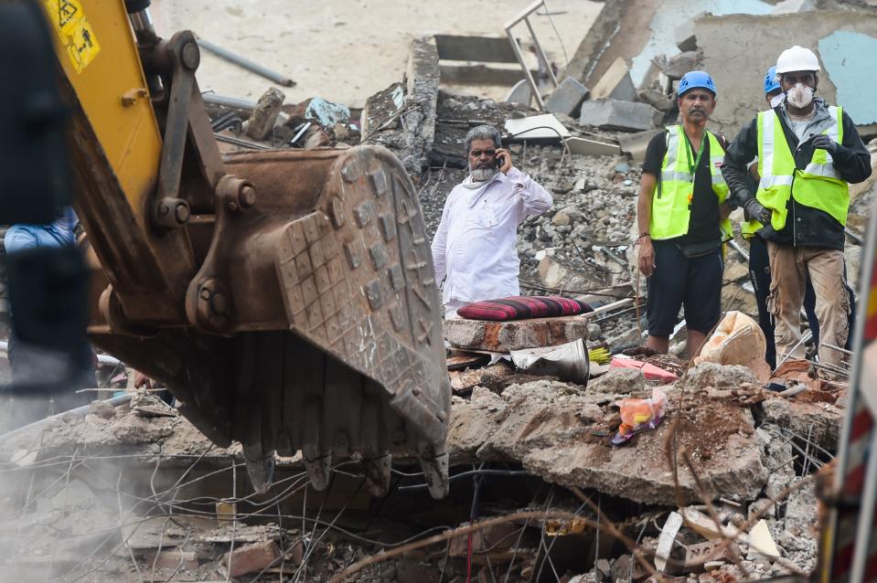 Rescue workers search for survivors in the rubble of a collapsed five-storey apartment building in Mahad. (Photo by PUNIT PARANJPE/AFP via Getty Images)