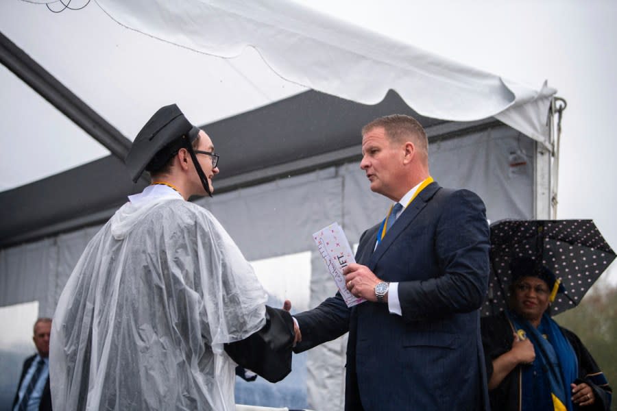 In this photo provided by University of Massachusetts Dartmouth, is billionaire Robert Hale, right, with a graduate student onstage at the graduation ceremony Thursday, May 16, 2024, in Dartmouth, Mass. Hale gifted graduates at the University of Massachusetts Dartmouth each with $1,000., with the condition that they give $500 away. Hale revealed the gift to more than 1,100 graduates. (Karl Christoff Dominey/University of Massachusetts Dartmouth via AP)