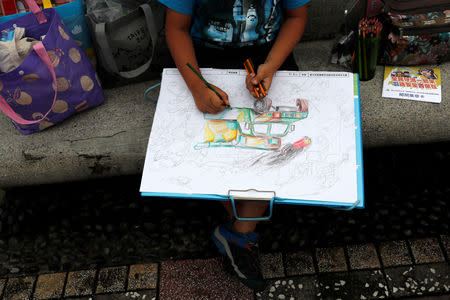 A child draws a picture of military vehicle during a public fair which displays military equipments, in Taipei, Taiwan September 29, 2018. Picture taken September 29, 2018. REUTERS/Tyrone Siu