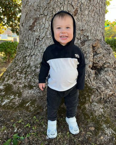 <p>Shawn Johnson Instagram </p> Shawn Johnson and Andrew East's son Jett James East posing next to a tree.