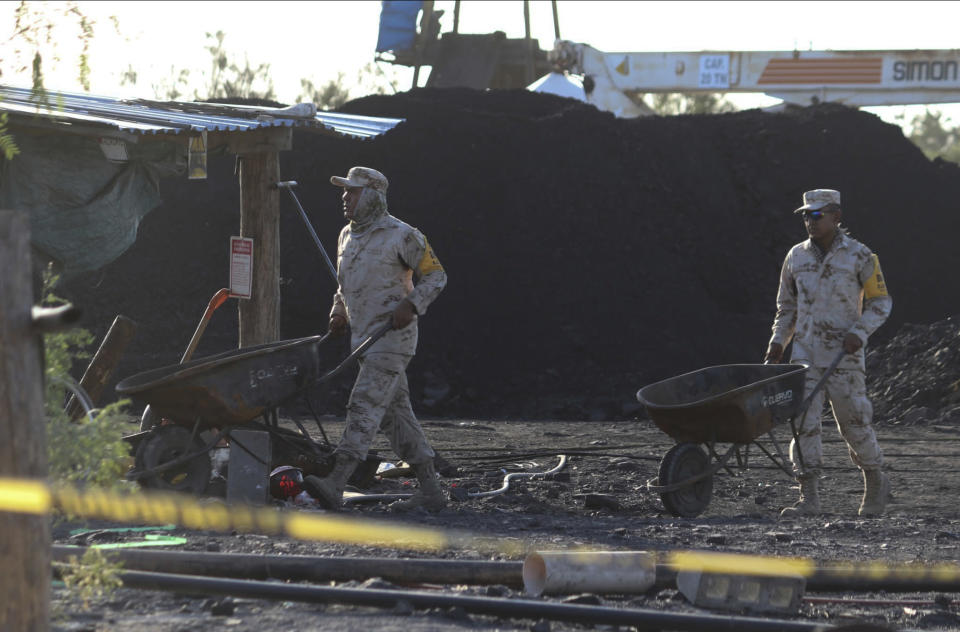 Mexican soldiers move wheelbarrows as they help in the rescue of 10 miners trapped in a collapsed and flooded coal mine in Sabinas, Coahuila state, Mexico, Thursday, Aug. 4, 2022. The collapse occurred after the miners breached a neighboring area filled with water on Wednesday, officials said. (AP Photo/Alfredo Lara)