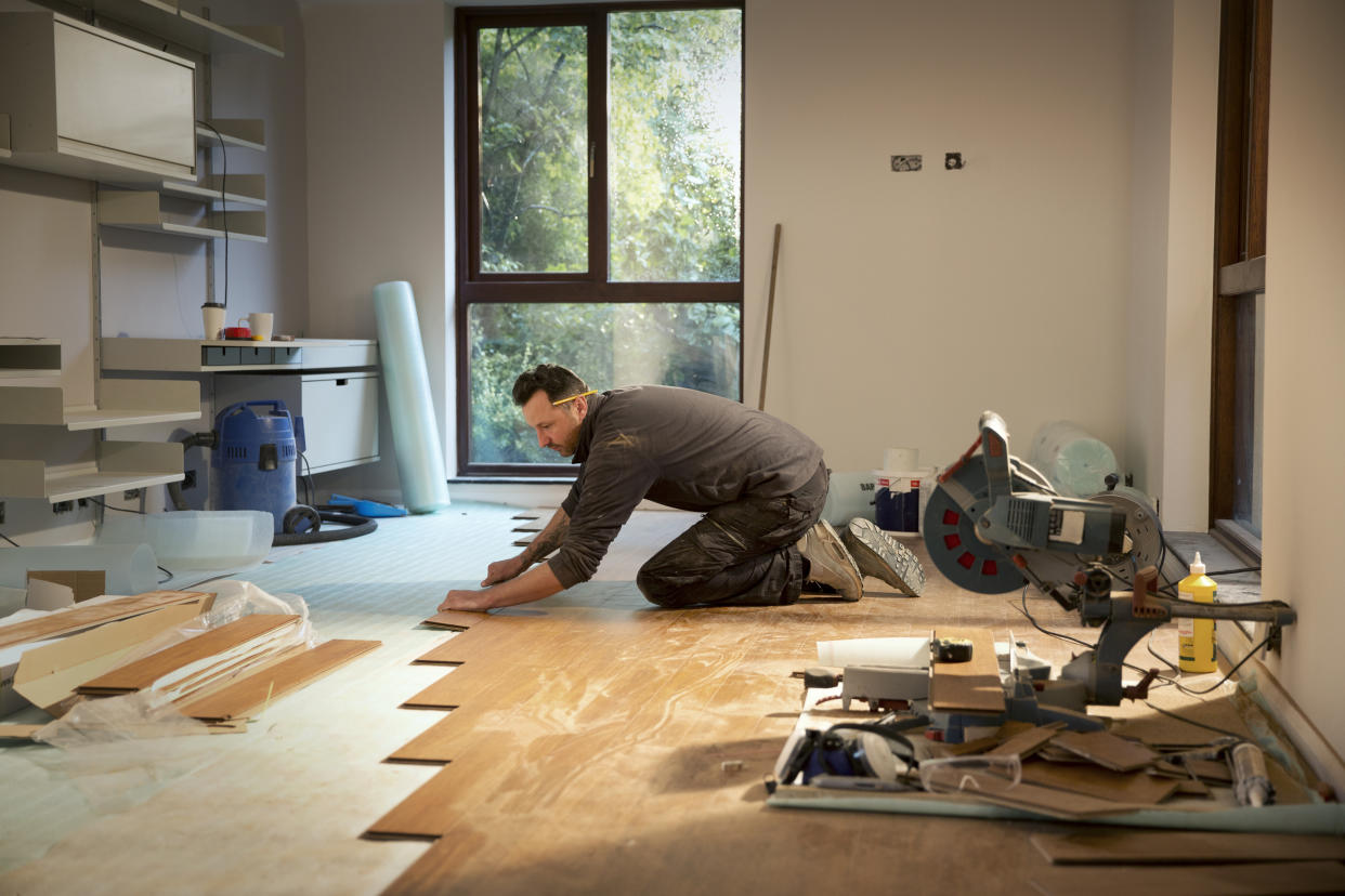 Construction worker laying hardwood flooring in house