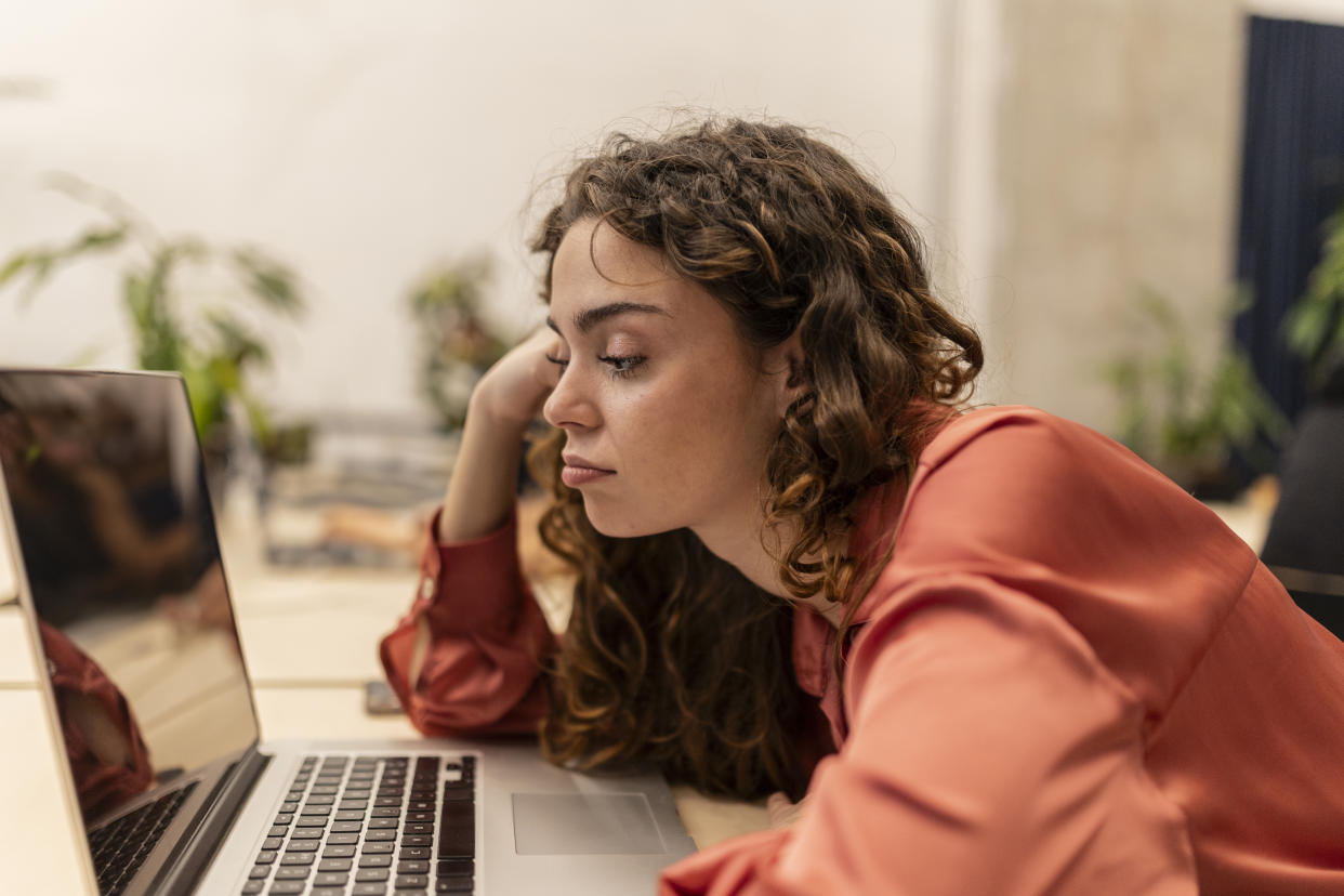 A young woman looks at a laptop screen.