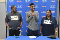 In this Jan. 31, 2020, photo provided by Tim Foster, Savion Johnson, center, stands with his father Patrick, left, and mother, Sabrina, after he signed his acceptance letter to Notre Dame de Namur University during a ceremony at the College of the Sequoias gym in Visalia, Calif. Savion was set to transfer this fall from a junior college in California to Notre Dame de Namur University in the San Francisco Bay Area as a Division 2 basketball recruit. As the coronavirus spread, Johnson received a text from the basketball coach rescinding his offer. The school, immersed in deep financial problems amid dwindling enrollment, decided to cancel the incoming freshman class and competitive sports as it tries to avert total closure. (Tim Foster via AP)