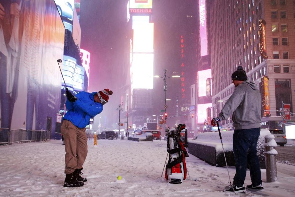 Two men play golf with a tennis ball as a snowstorm sweeps through Times Square, Tuesday, March 14, 2017, in New York. A powerful nor'easter hit the Northeast on Tuesday after a largely uneventful winter, grounding thousands of flights and leading to school and work closures along the coast. (AP Photo/Mark Lennihan)