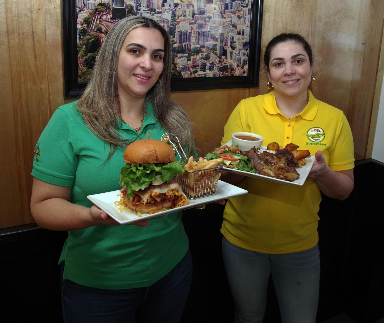 Taste of Brazil co-owners and sisters Jacqualine Macedo of Hanson and Aline Macedo of Whitman hold up their X Brazil sandwich and Plate of The Day dishes, two of the more popular entrees they serves at their very popular restaurant on Crescent Street in Brockton on Thursday, March 16, 2023.