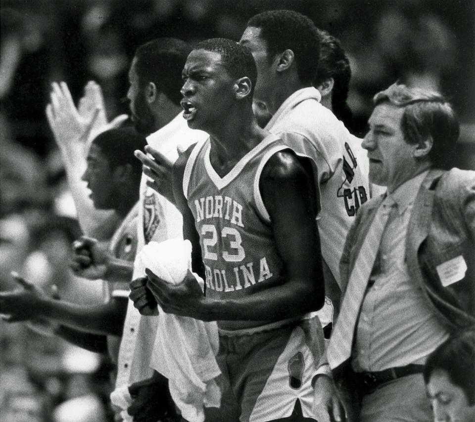 North Carolina's Michael Jordan (23) cheers from the bench as the Tar Heels win another game for head coach Dean Smith, right, in Raleigh on Nov. 15 1983.