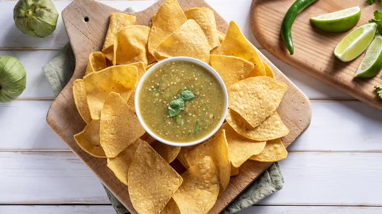 tortilla chips surrounding slasa verde on a white table