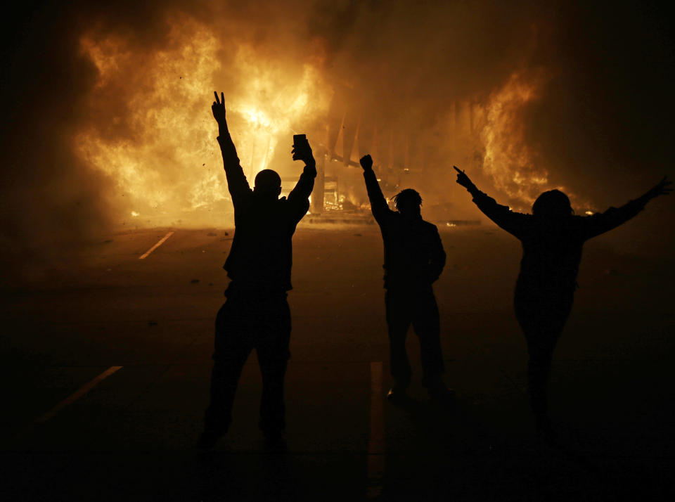 FILE - In this Nov. 25, 2014, file photo, people watch as stores burn in Ferguson, Mo. Michael Brown's death five years ago at the hands of a white Missouri police officer stands as a seismic moment of race relations in America. (AP Photo/David Goldman, File)