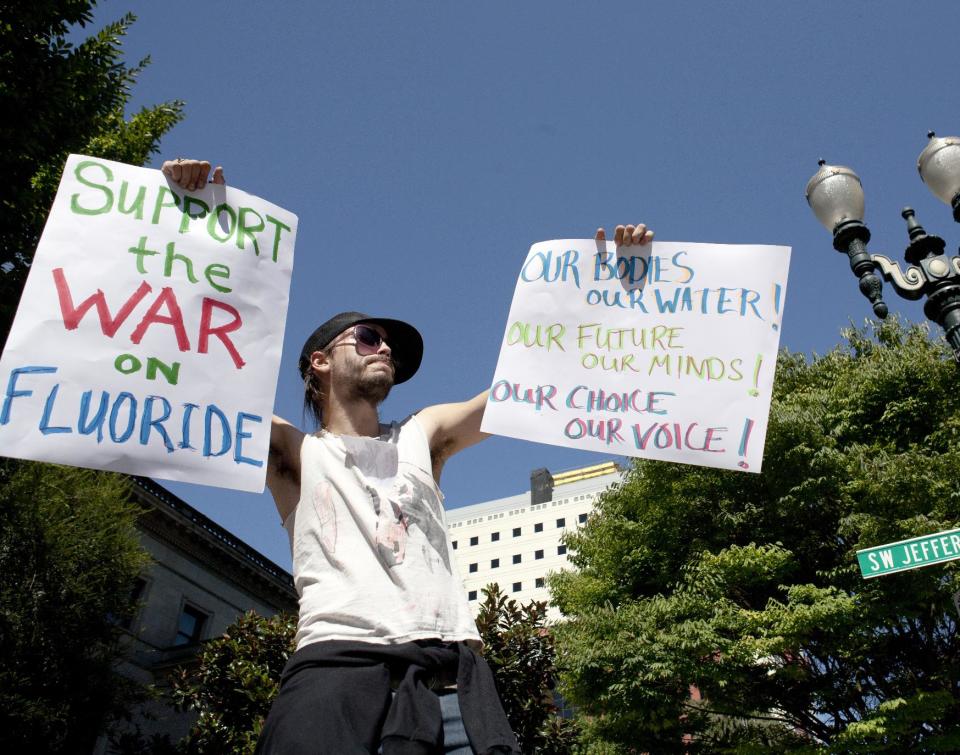 FILE - In this Thursday, Sept. 6, 2012 file photo, demonstrator China Starshine holds up signs outside of City Hall where the Portland City Council opened public testimony on Commissioner Randy Leonard's plan to fluoridate the area's drinking water in Portland, Ore. Portland is the largest city in the United States that has yet to approve fluoridation to combat tooth decay, a distinction set to change at a City Council meeting on Wednesday, Sept. 12, 2012. Many in Portland and the state at large have long opposed public fluoridation, saying it's unsafe and violates an individual's right to consent to medication. While 73 percent of the U.S. population drinks water treated with fluoride, the rate is less than 25 percent in Oregon. (AP Photo/The Oregonian, Ross William Hamilton) MAGS OUT; TV OUT; LOCAL TV OUT; LOCAL INTERNET OUT; THE MERCURY OUT; WILLAMETTE WEEK OUT; PAMPLIN MEDIA GROUP OUT