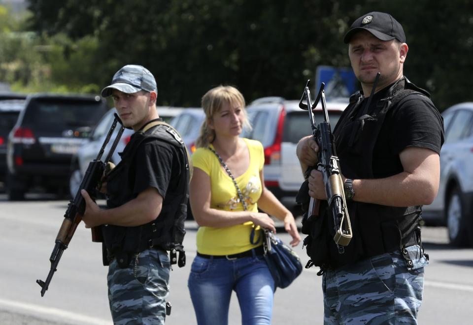A woman walks past armed pro-Russian separatists who stand guard on the suburbs of Shakhtarsk, Donetsk region July 28, 2014. REUTERS/Sergei Karpukhin (UKRAINE - Tags: POLITICS CIVIL UNREST MILITARY CONFLICT)