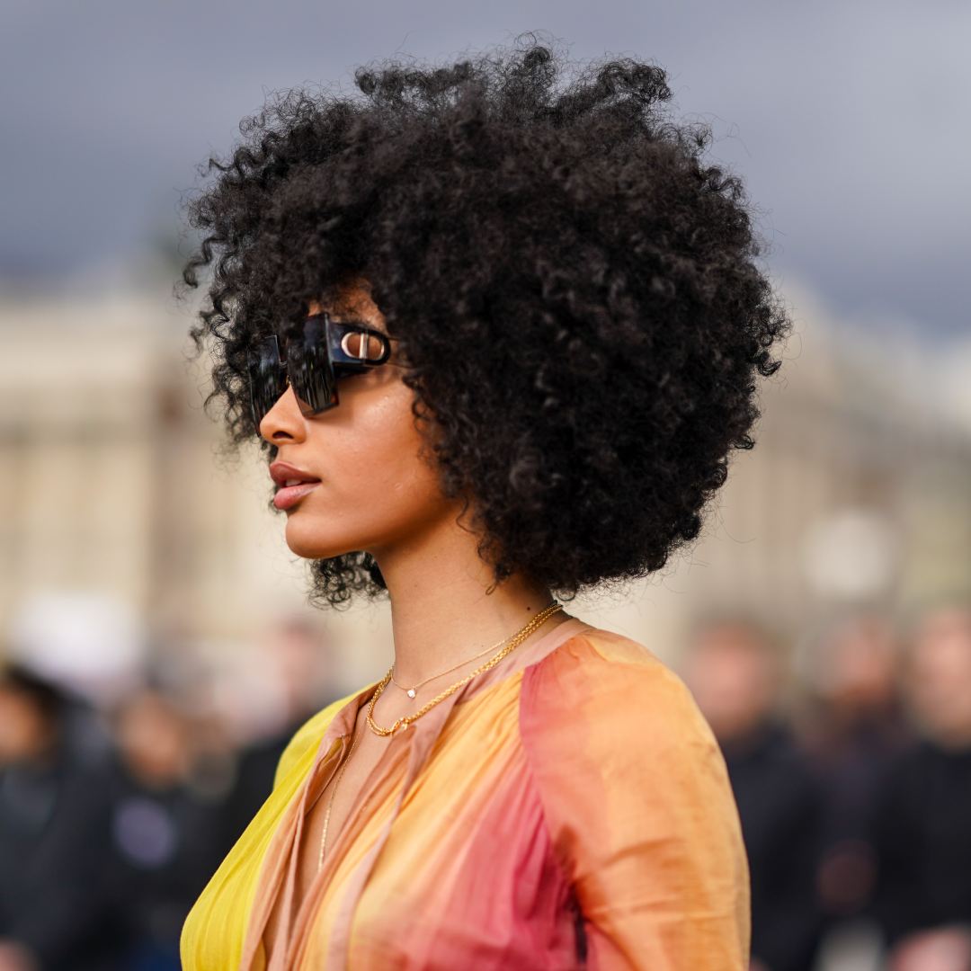  A guest wears Dior sunglasss, a yellow and pink pleated dress, outside Dior, during Paris Fashion Week - Womenswear Fall/Winter 2020/2021, on February 25, 2020 in Paris, France. 