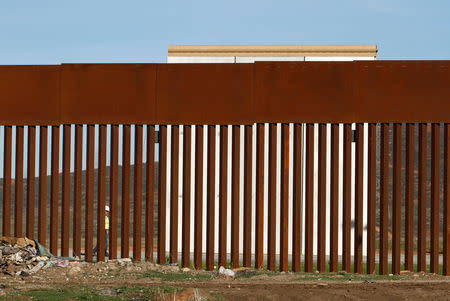 A worker walks near a prototype for U.S. President Donald Trump's border wall, as seen through the border fence between Mexico and the United States, in Tijuana, Mexico January 7, 2019. REUTERS/Jorge Duenes