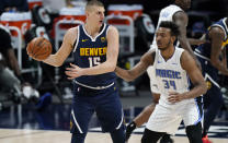 Denver Nuggets center Nikola Jokic, left, looks to pass the ball as Orlando Magic center Wendell Carter Jr. defends in the first half of an NBA basketball game, Sunday, April 4, 2021, in Denver. (AP Photo/David Zalubowski)