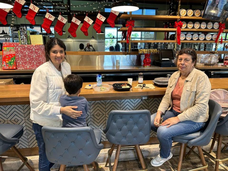 Andrea Garcia, her son, and her mom, Teresa Garcia, take a break while dining at Whole Foods’ cafe section on Dec. 7, 2023. The family shops for groceries at the Pinecrest location and for convenience brings food over from the hot and cold salad bars to get lunch and shopping done on one trip to the store.