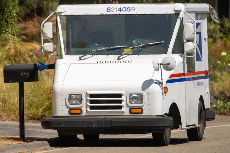 A U.S. postal service worker delivers mail during the outbreak of the coronavirus disease in California