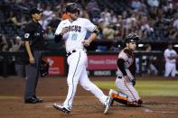 Arizona Diamondbacks' Carson Kelly (18) looks back after scoring a run as San Francisco Giants catcher Austin Wynns, right, and umpire Gabe Morales (47) pause at home plate during the fifth inning of a baseball game Tuesday, July 5, 2022, in Phoenix. (AP Photo/Ross D. Franklin)