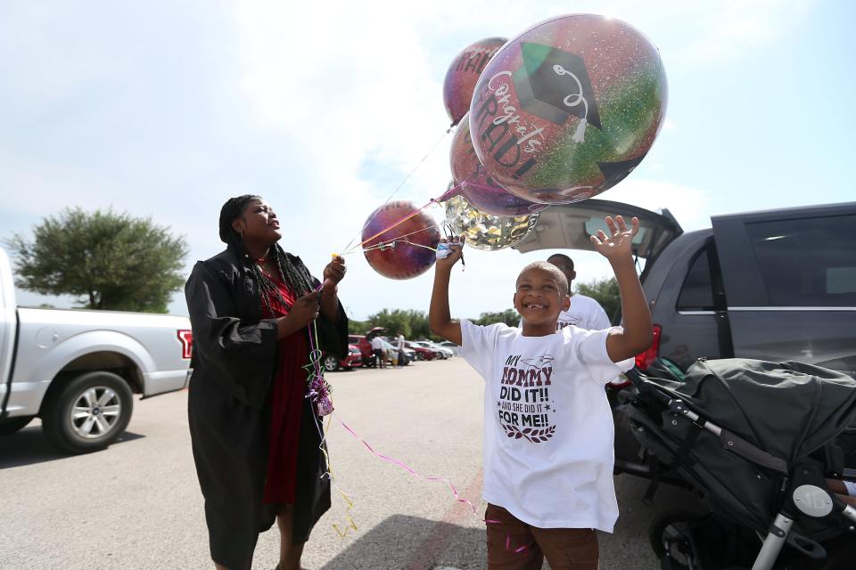 Shilda Fresch tries to keep her balloons from blowing away while son Jackson Fresch plays with them before her graduation ceremony from Austin Community College on May 13 at H-E-B Center at Cedar Park.