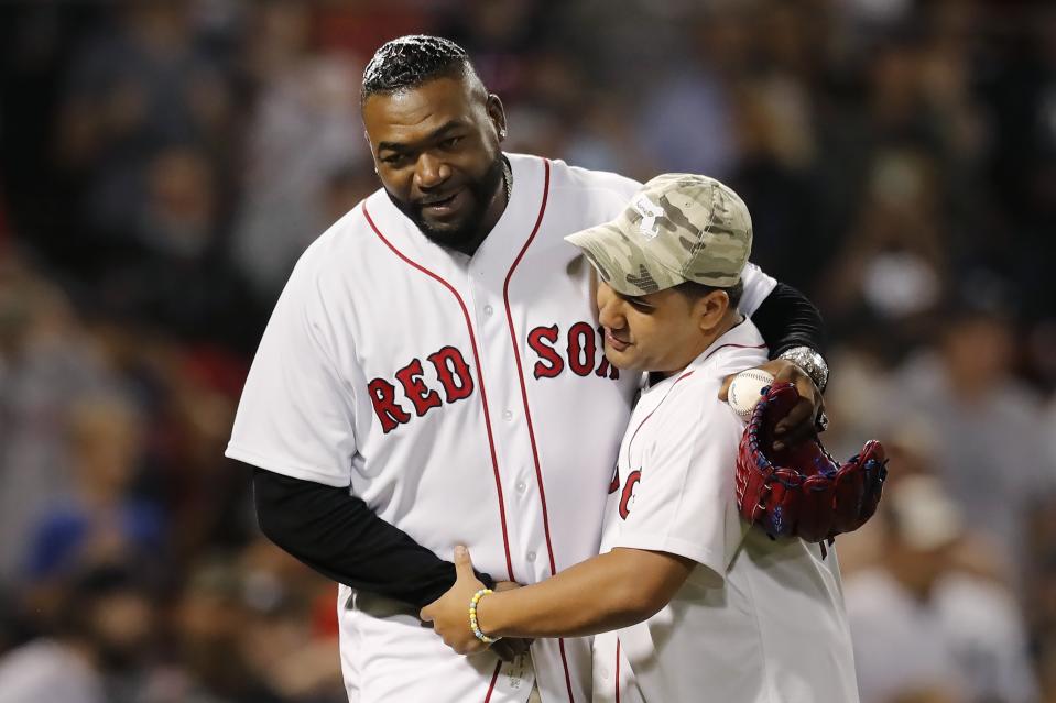 Former Boston Red Sox's David Ortiz, left, hugs Yolbin Rosario after Rosario threw out the ceremonial first pitch before a baseball game against the New York Yankees, Sunday, Sept. 26, 2021, in Boston. Rosario is the brother of Sgt. Johanny Rosario Pichardo, a U.S. Marine who was among 13 service members killed in a suicide bombing in Afghanistan. (AP Photo/Michael Dwyer)