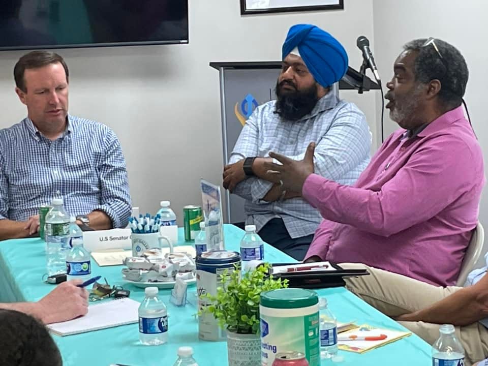 U.S. Senator Chris Murphy talks with Sikh Art Gallery Creative Director Swaranjit Singh Khalsa and Rev. Greg Perry of the Greenville Congregational Church during a Norwich Interfaith Association meeting about combating loneliness among American adults.
