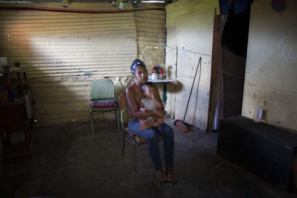 In this photo taken July 25, 2019, Karelys Herrera, 15, holds her baby inside her home during a interview in the Caucaguita neighborhood on the outskirts of Caracas, Venezuela. Herrera said she contemplated suicide after learning she was pregnant at age 14. (AP Photo/Ariana Cubillos)