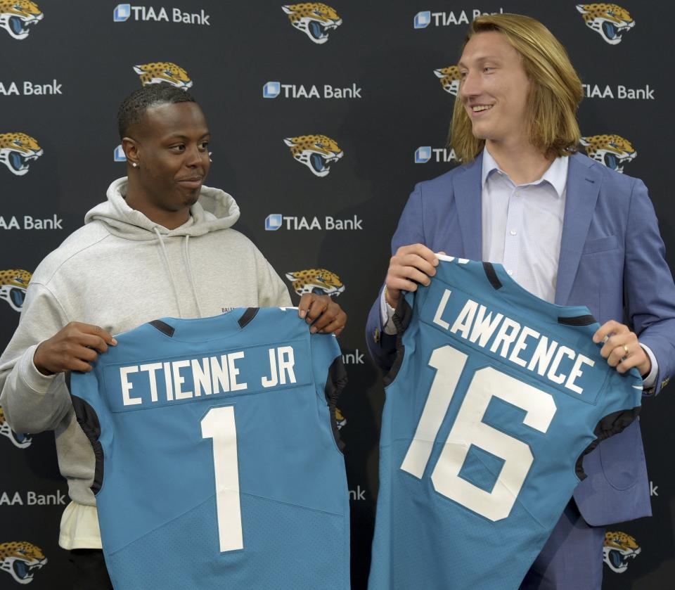 Former Clemson teammates Travis Etienne and Trevor Lawrence and now Jacksonville Jaguars teammates with their new jerseys during an introductory press conference Friday, April 30, 2021, in Jacksonville, Fla.  (Bob Self/The Florida Times-Union via AP)