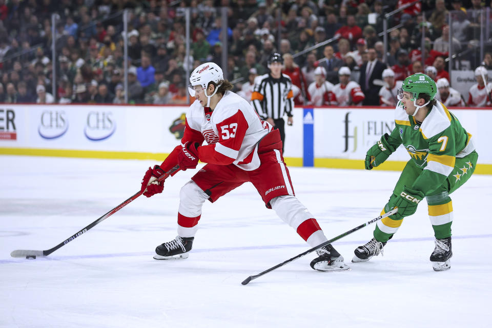 Detroit Red Wings defenseman Moritz Seider (53) skates with the puck alongside Minnesota Wild defenseman Brock Faber (7) during the first period of an NHL hockey game Wednesday, Dec. 27, 2023, in St. Paul, Minn. (AP Photo/Matt Krohn)