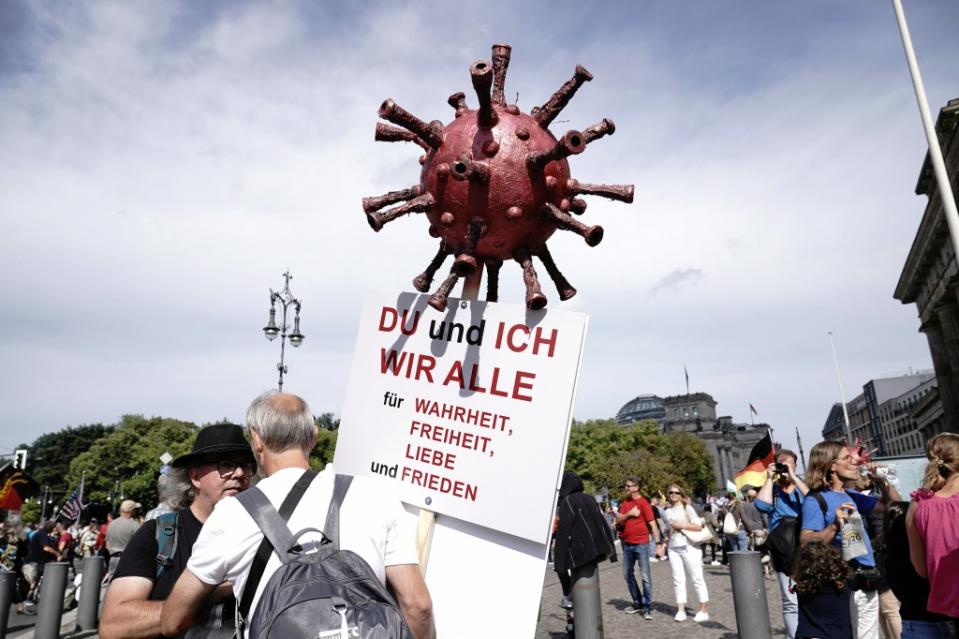 Ein Teilnehmer einer Demonstration gegen die Corona-Maßnahmen hält ein Schild "Du und ich wir alle für Wahrheit, Freiheit, Liebe und Frieden" und einer Nachbildung des Corona-Virus.<span class="copyright">Michael Kappeler / dpa</span>