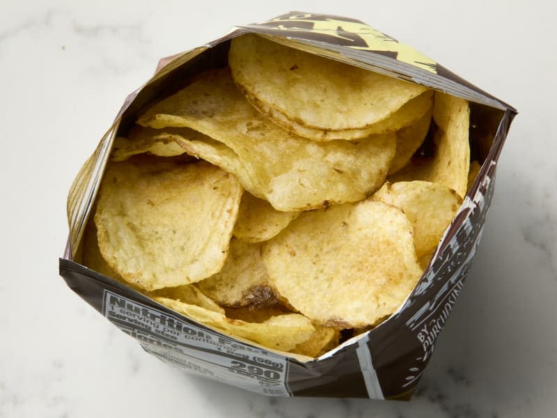 overhead shot of an opened bag of kettle chips on a marble surface