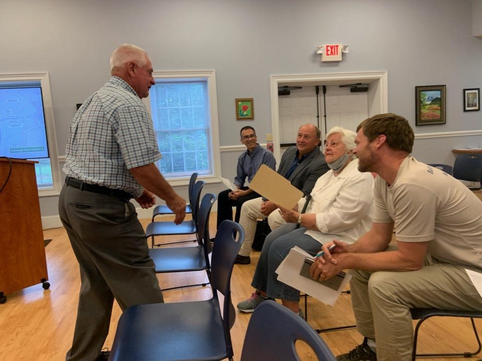 Mars Hill Mayor John Chandler presents Richard L. Hoffman's son and wife, Lee and Jeanne Hoffman, with the town board's resolution renaming the Bailey Mountain Preserve's main trail after Richard L. Hoffman while WithersRavenel land engineer Dan Greenberg, second from left, and parks and recreation committee chair Ryan Bell, right, look on.