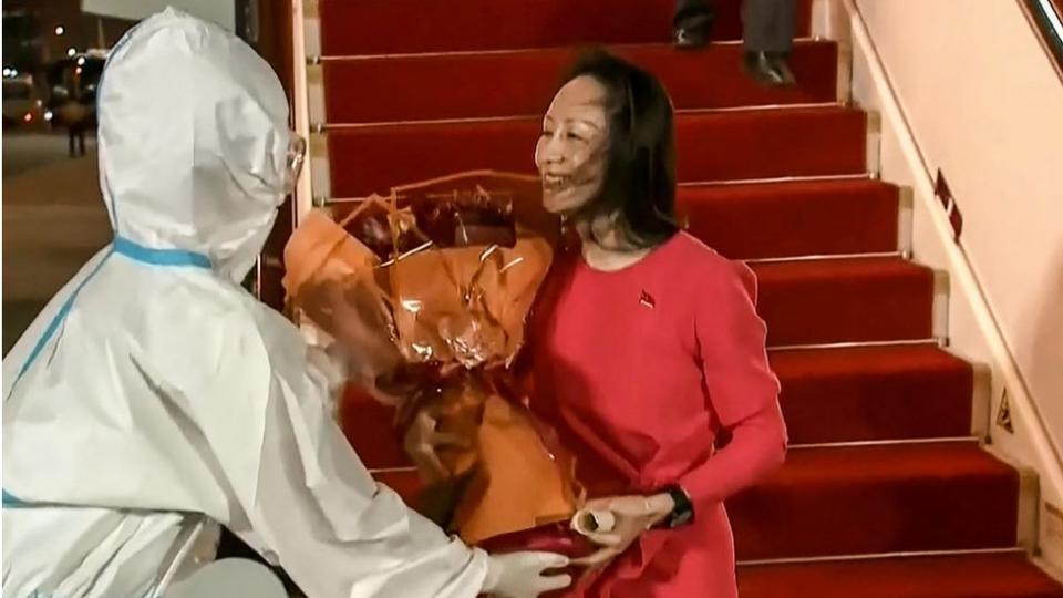 This screen grab made from video released by Chinese state broadcaster CCTV shows Huawei executive Meng Wanzhou receiving flowers after she arrived following her release