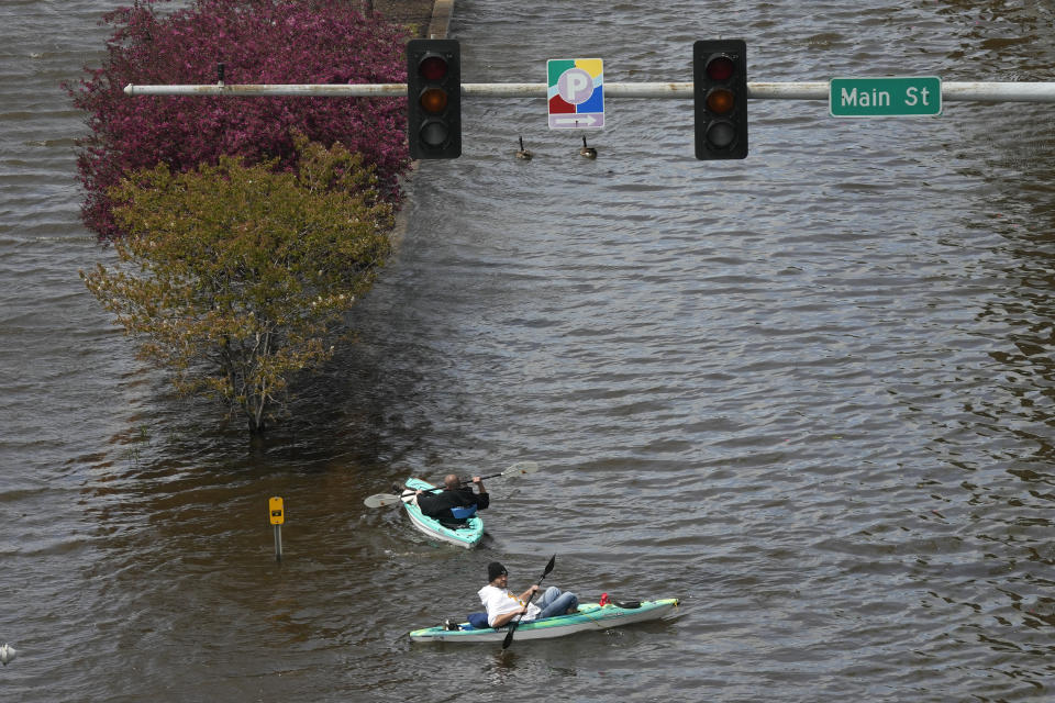Kayakers float down a flooded street, Monday, May 1, 2023, in downtown Davenport, Iowa. The rising Mississippi River is testing flood defenses in southeast Iowa and northwest Illinois as it nears forecast crests in the area Monday, driven by a spring surge of water from melting snow. (AP Photo/Charlie Neibergall)