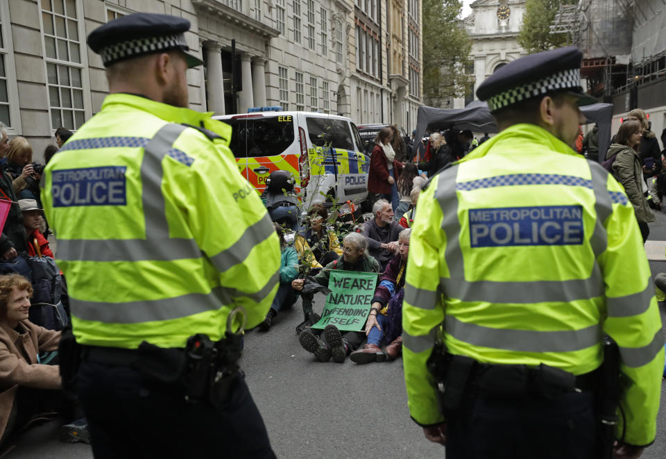 A climate protestor wears a banner reading "we are nature defending itself" when blocking a road in central London Monday, Oct. 7, 2019. (Photo: Matt Dunham/AP)